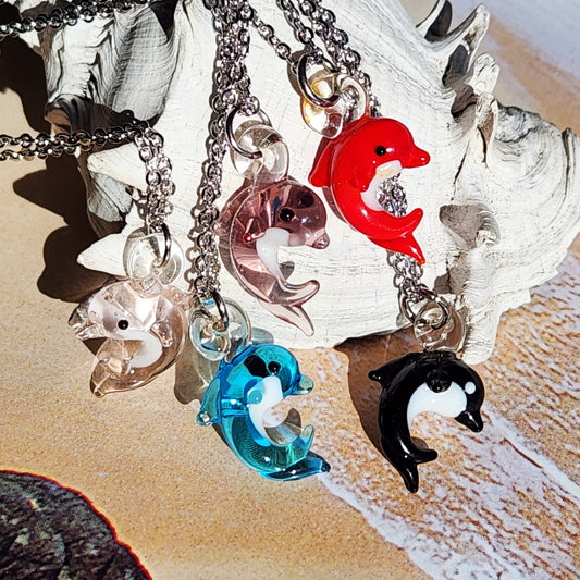 Necklace with dolphin charms on a shell and sand background