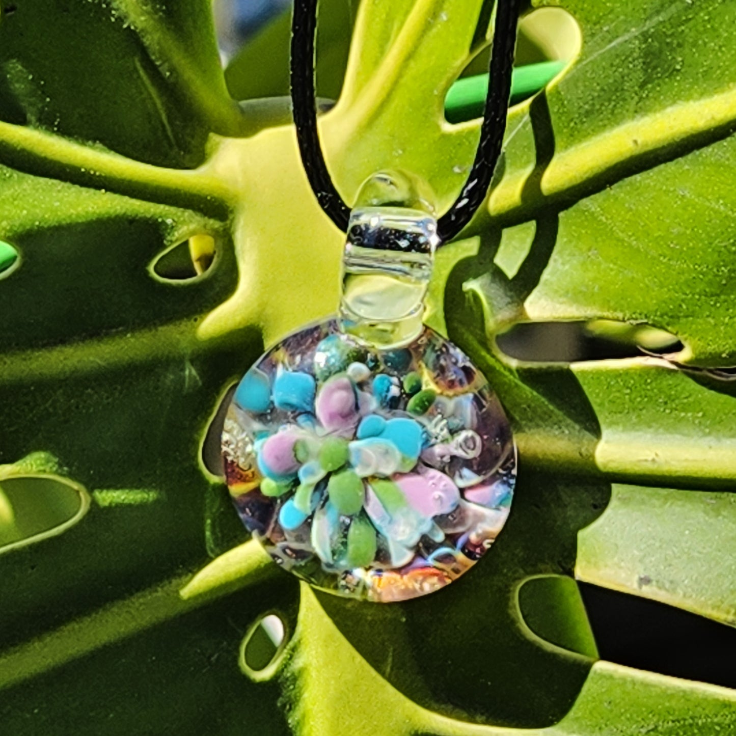 Colorful glass pendant displayed on green foliage
