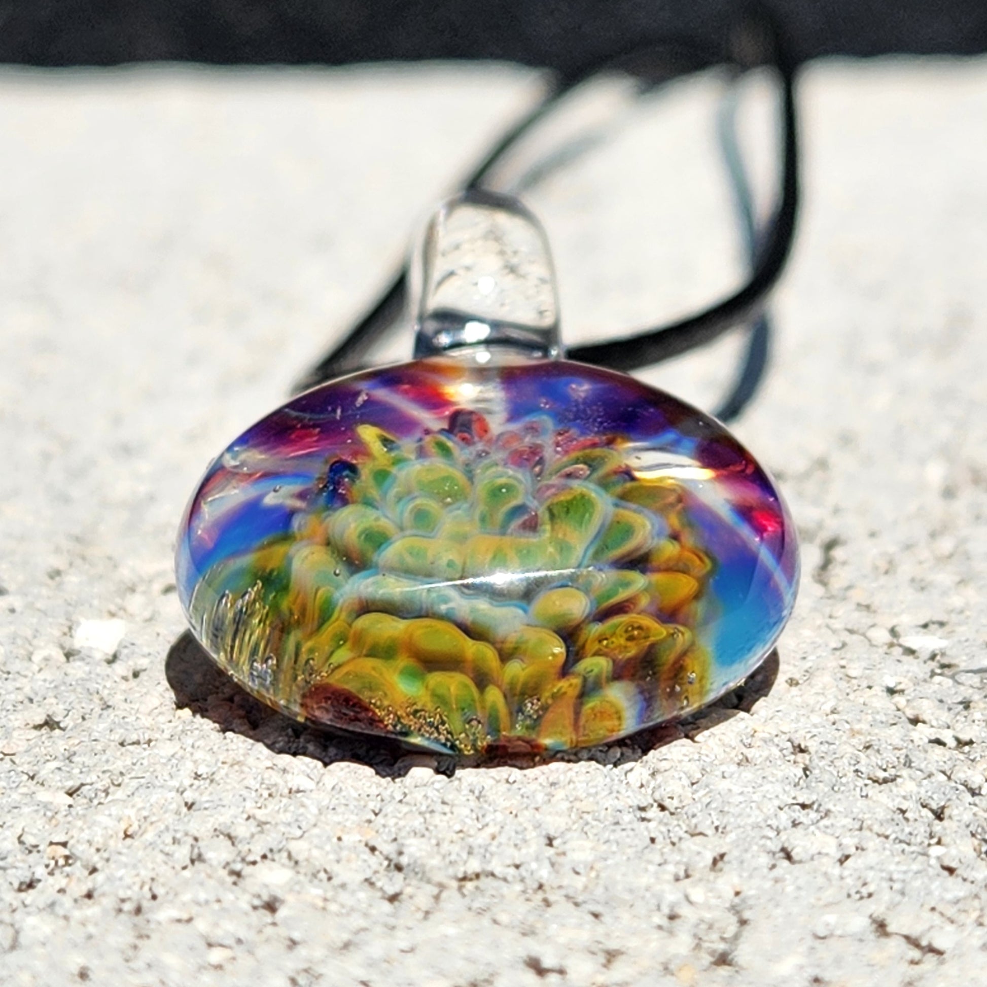 Colorful glass pendant necklace on sandy surface