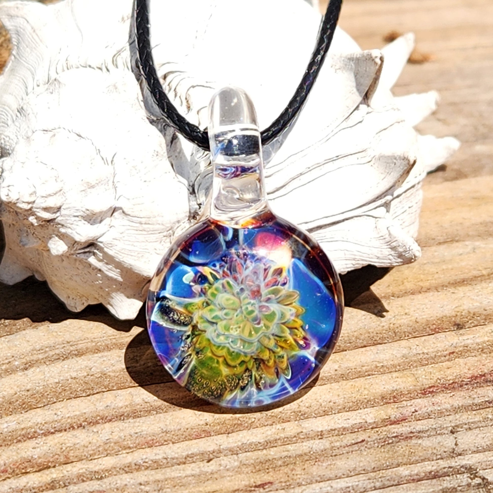 Vivid glass pendant necklace on sandy surface