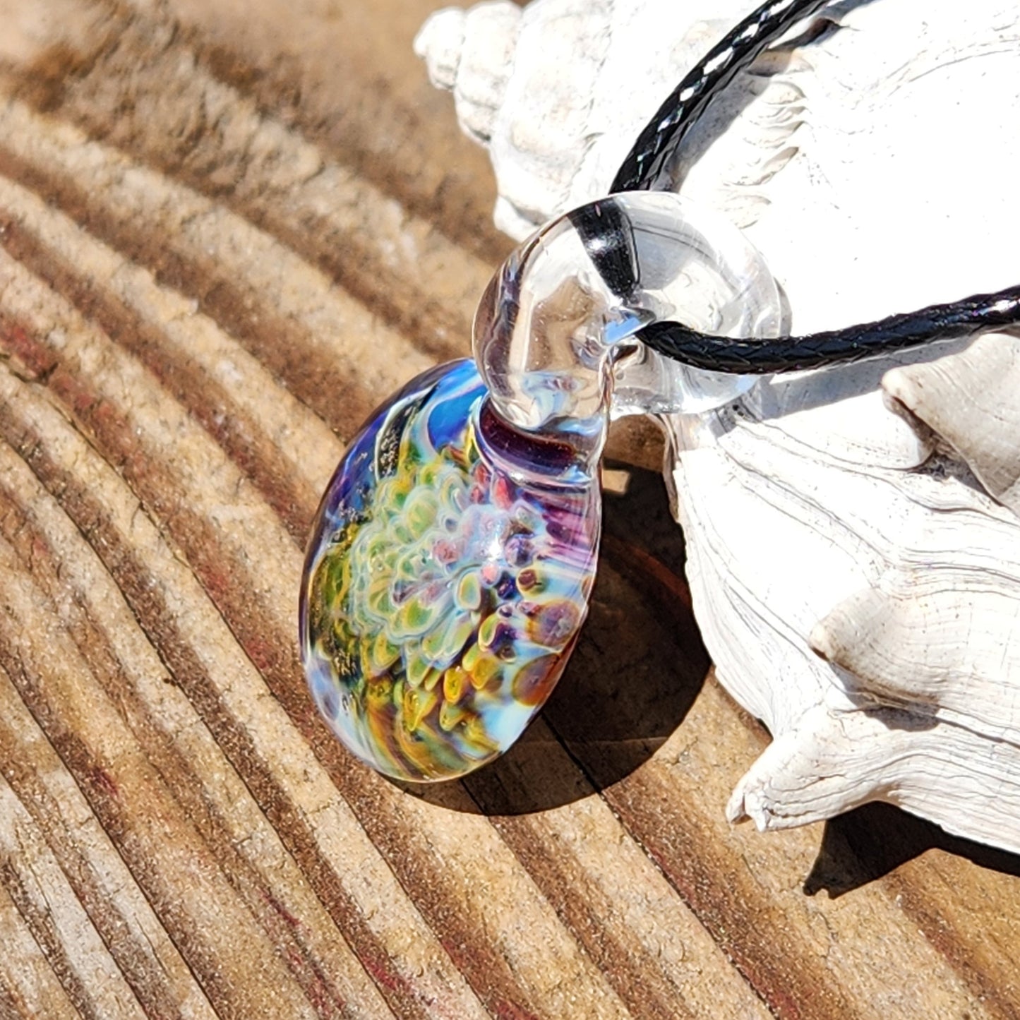 Colorful glass pendant necklace on wooden surface