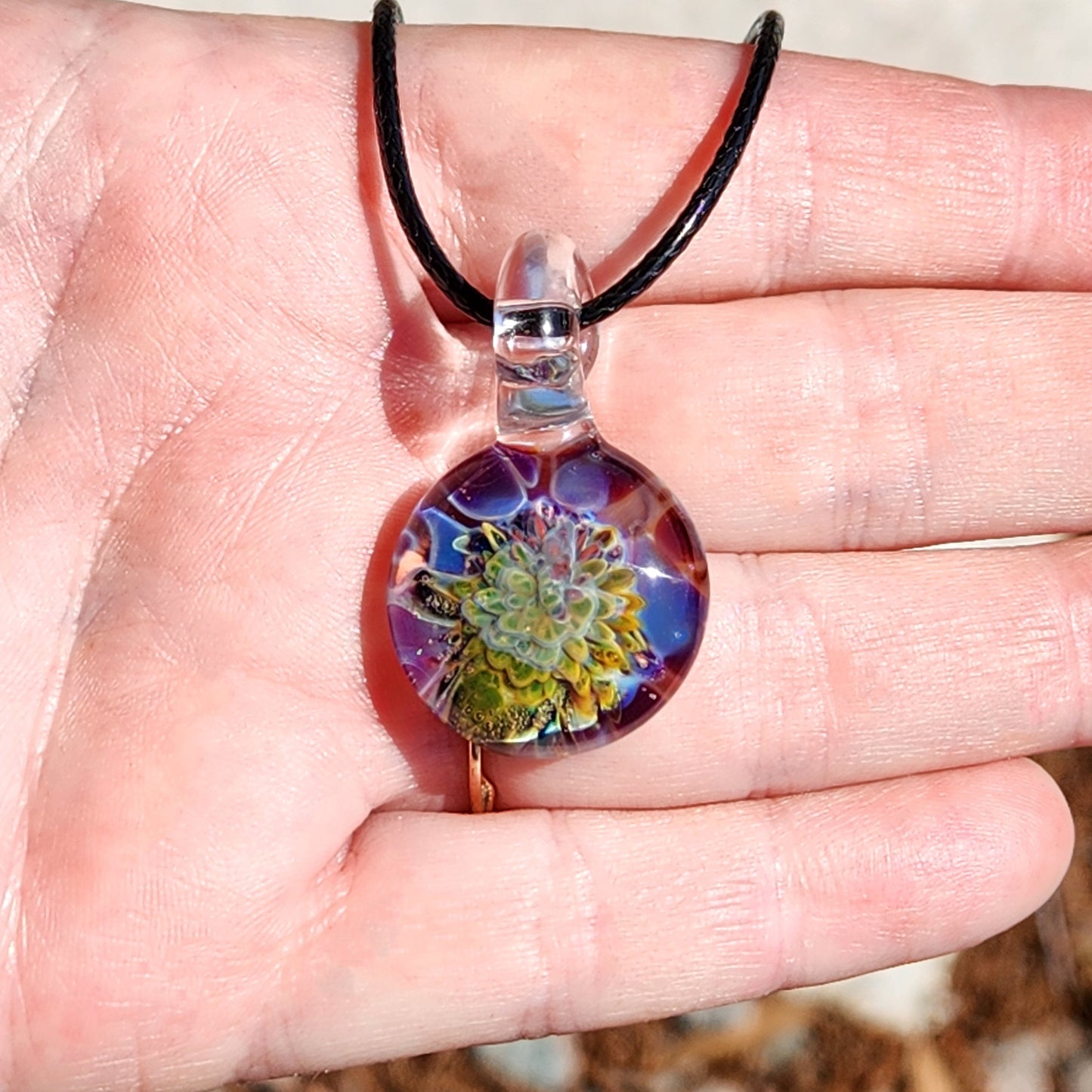 Green glass pendant necklace with colorful floral design on black cord