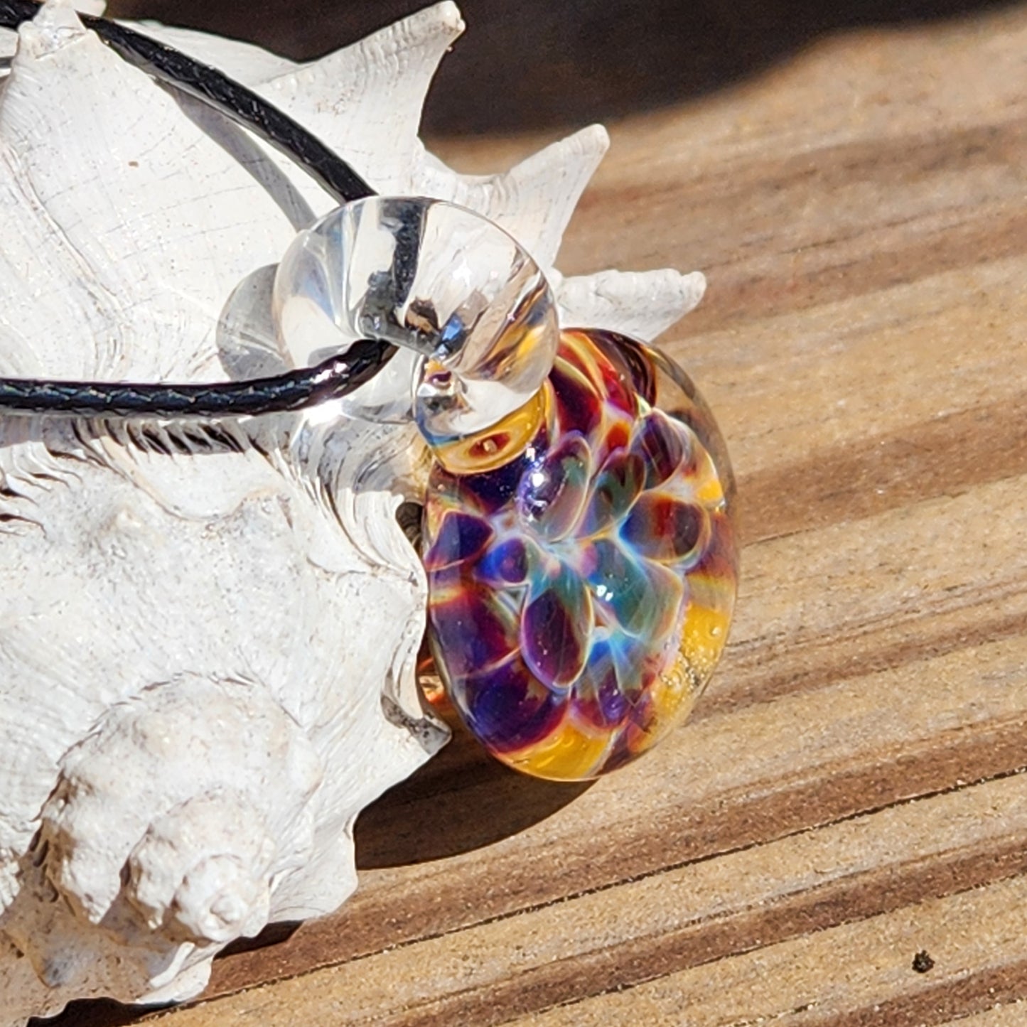 Colorful glass marble on a white shell with a wooden background
