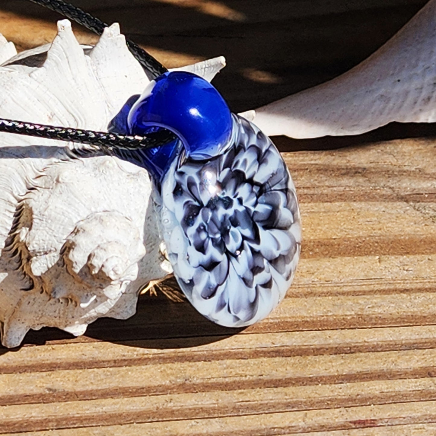 Close-up of blue glass pendant with black cord