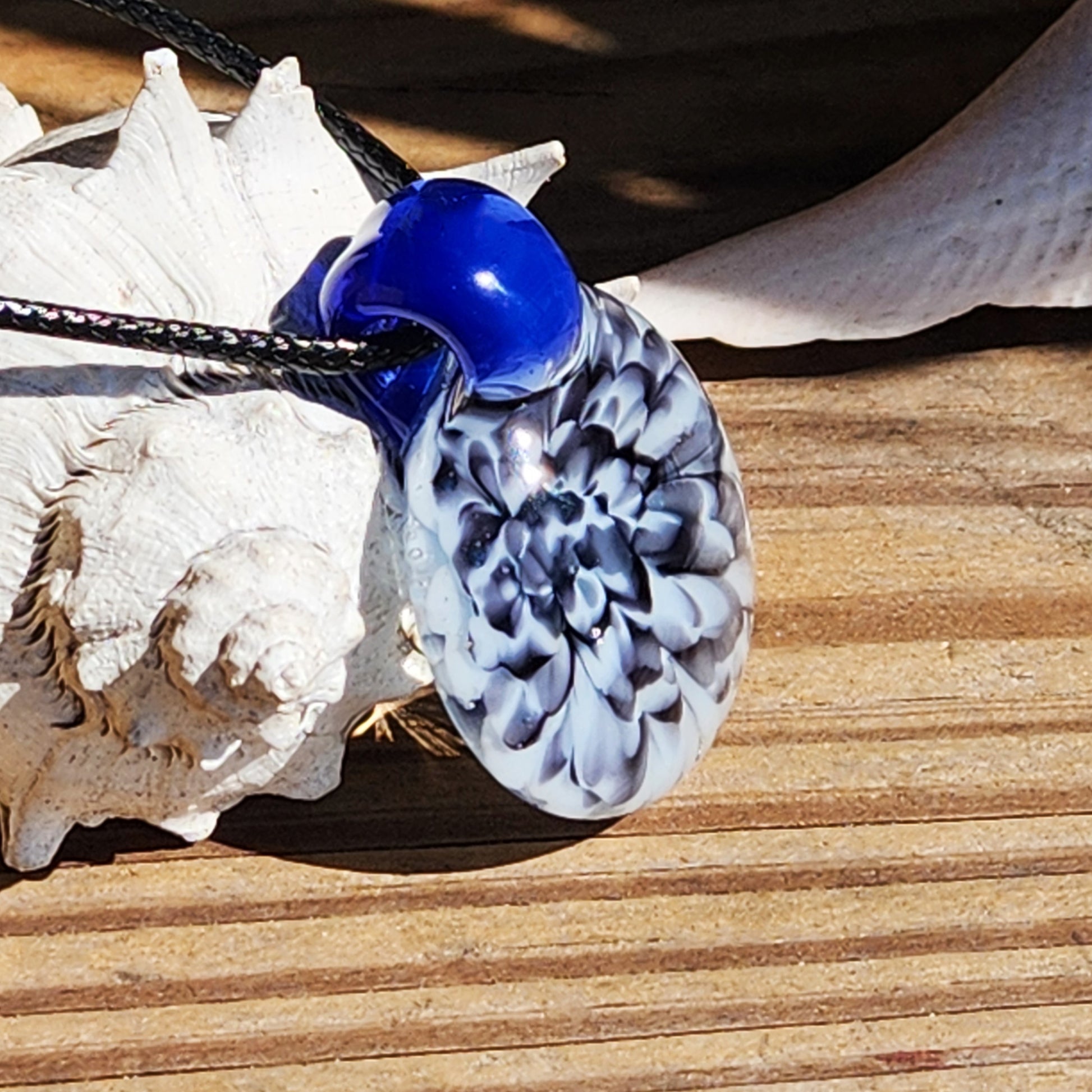 Close-up of blue glass pendant with black cord