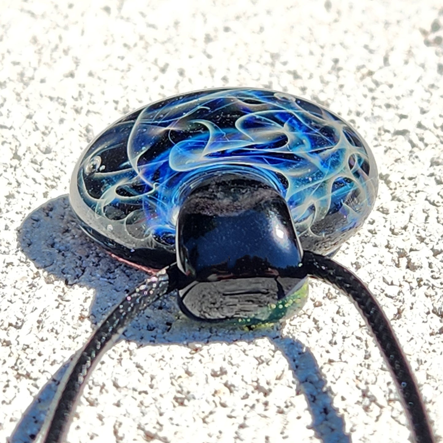 Close-up of glass pendant with swirling blue and white patterns