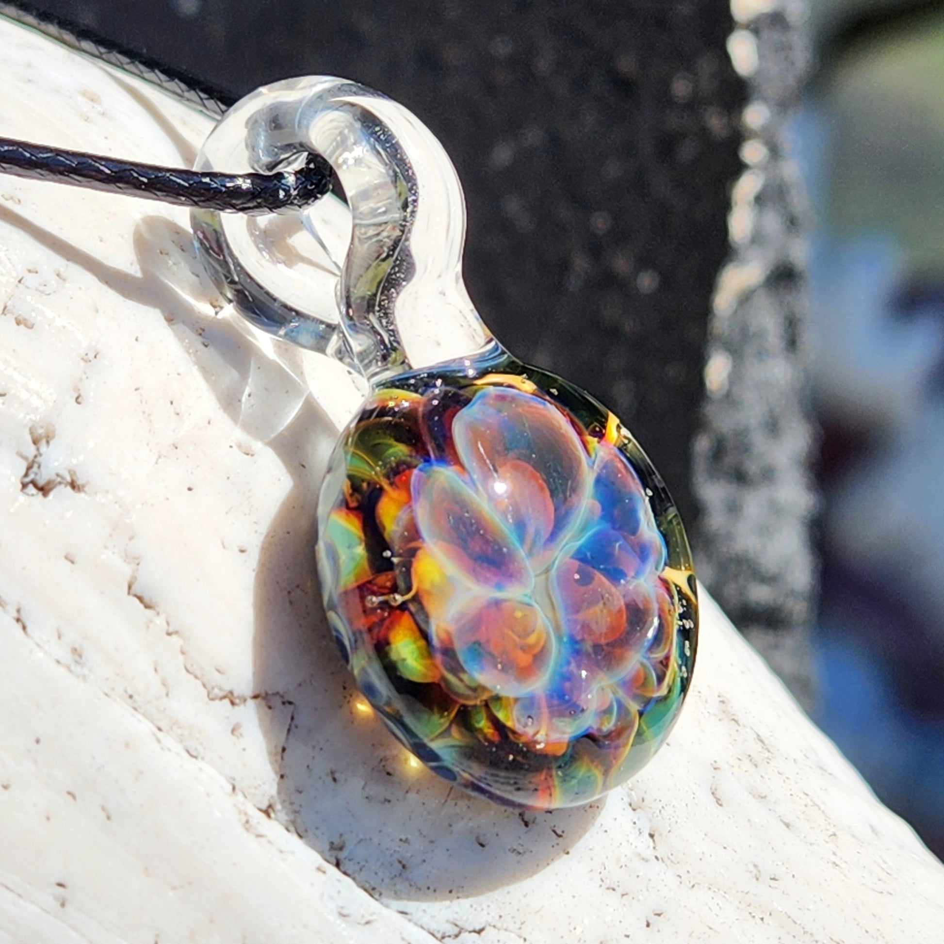 Close-up of glass pendant with black cord on white surface