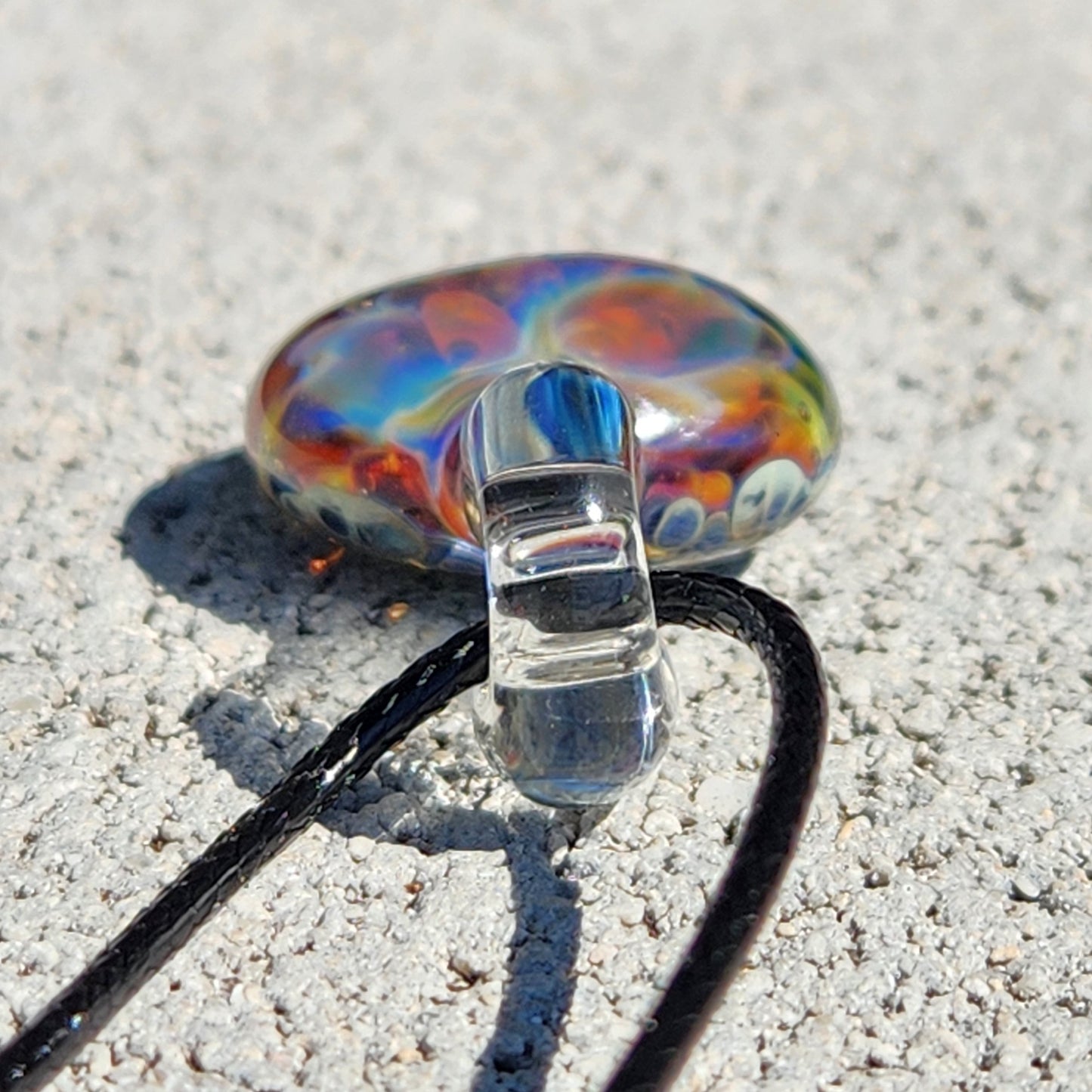 Colorful glass pendant on white textured surface