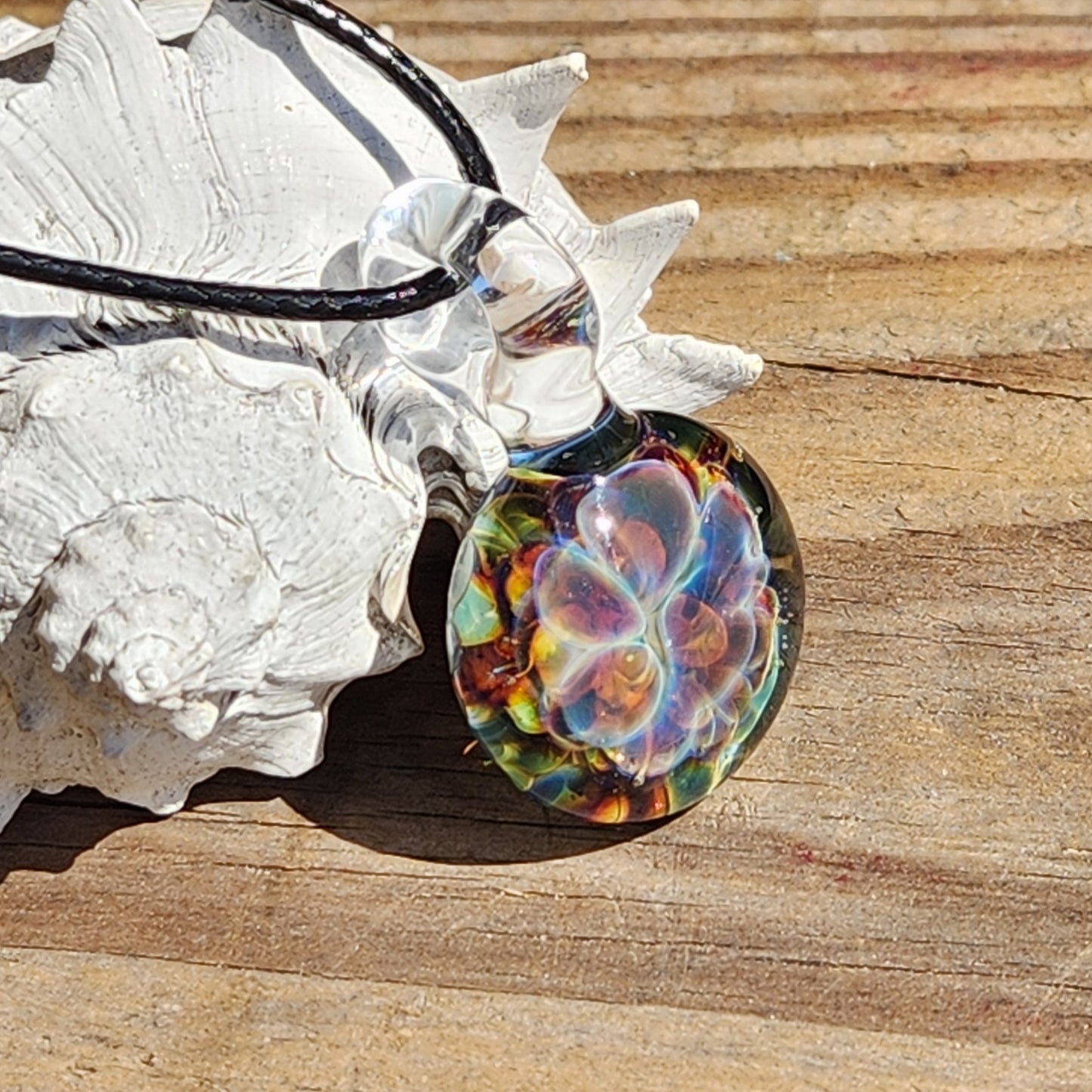 Close-up of glass pendant with black cord on wooden surface