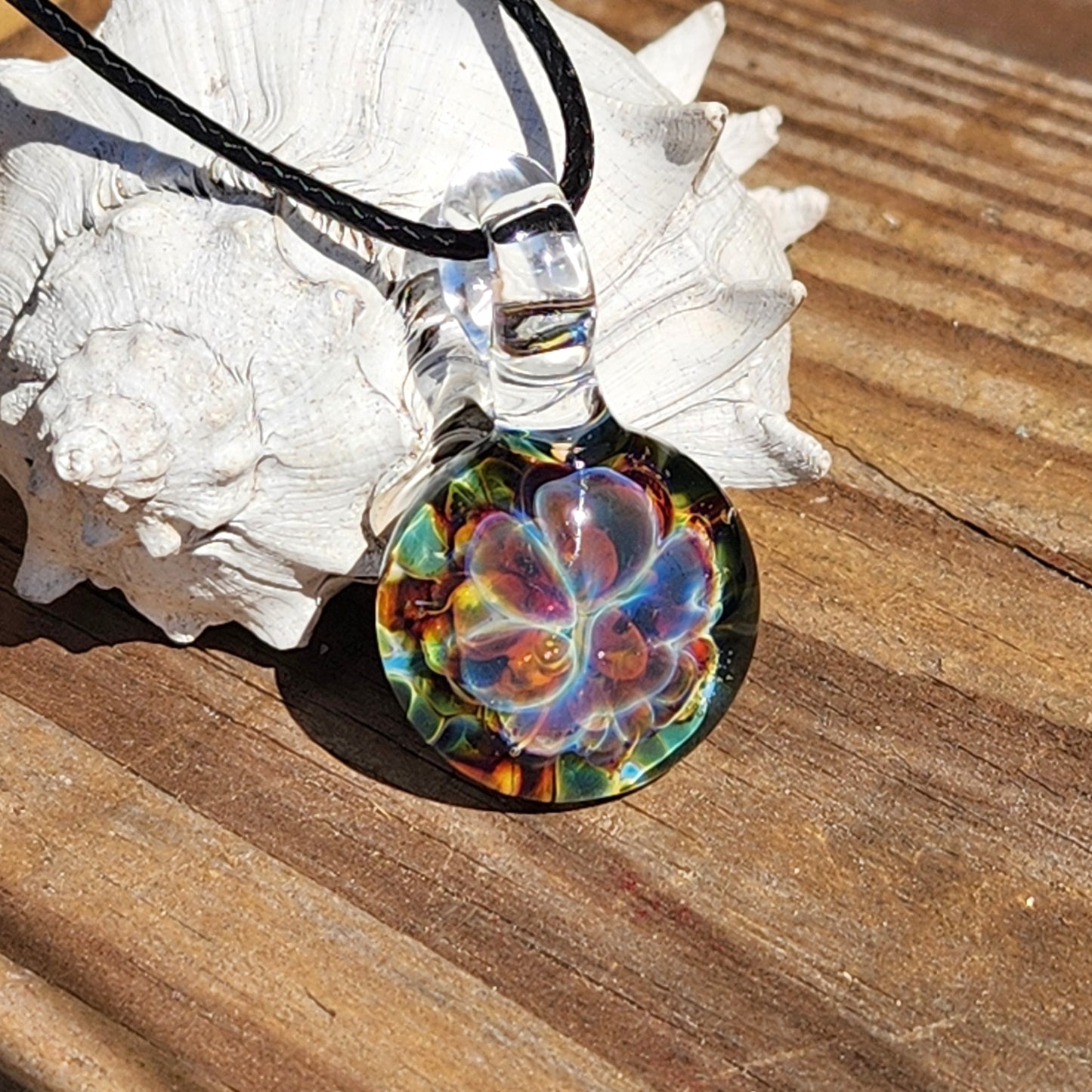 Colorful glass pendant with black cord on white textured background