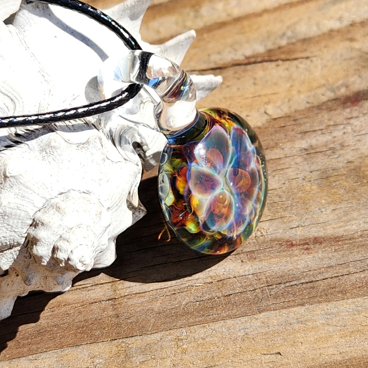 Colorful glass pendant necklace on white textured surface