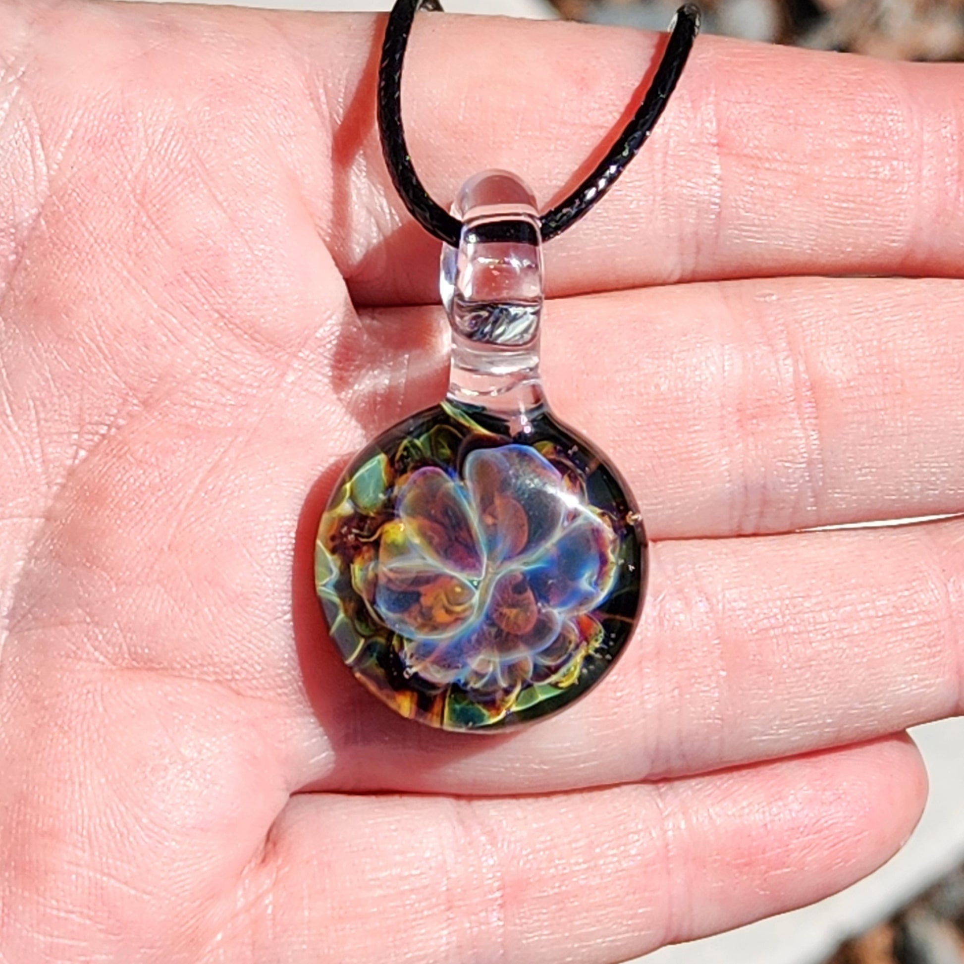 Necklace with colorful glass pendant on finger