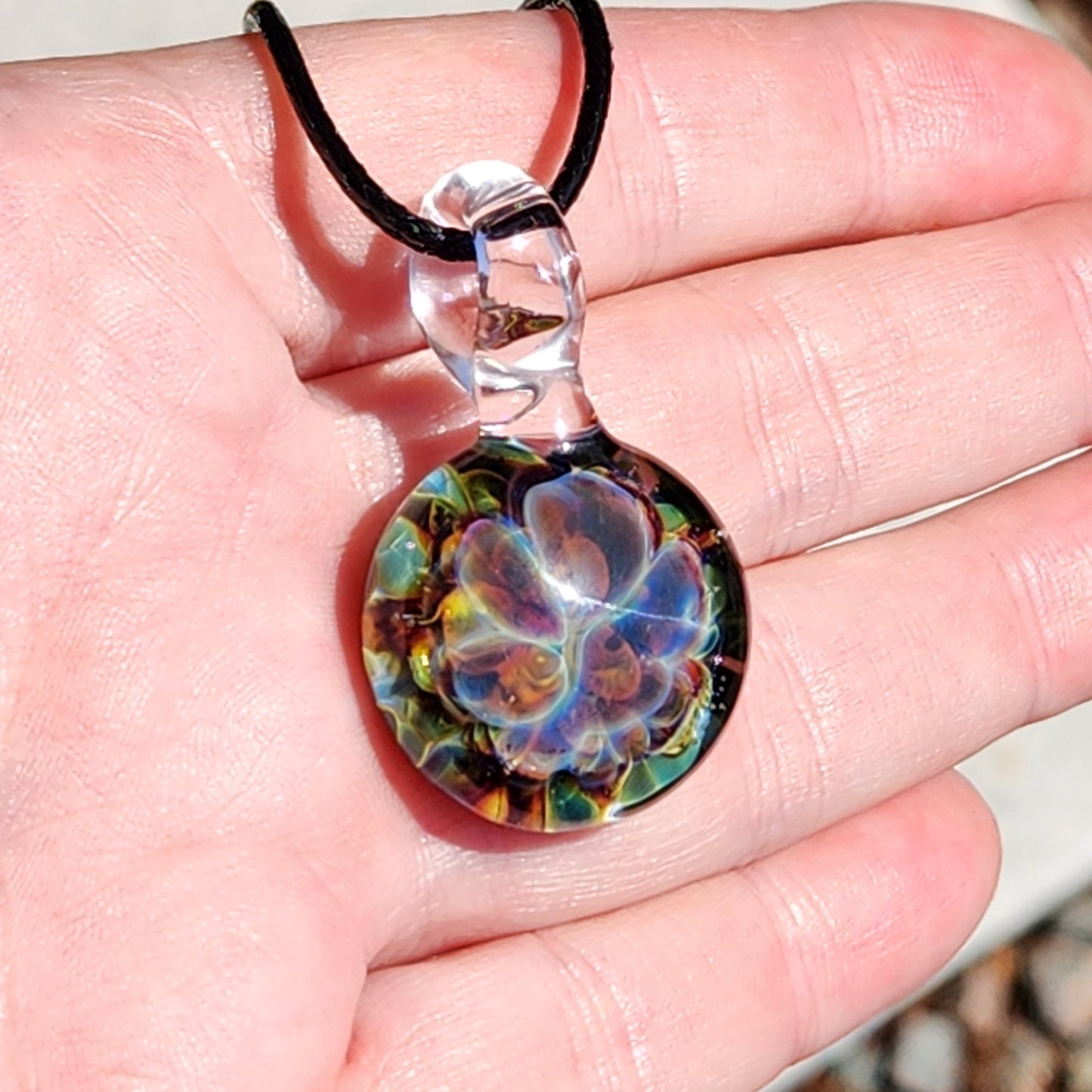 Glass pendant necklace worn on hand with wooden background