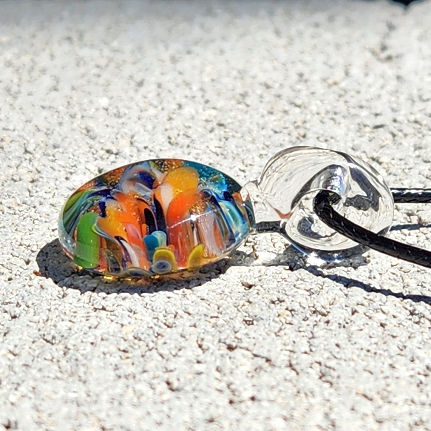 Colorful glass bead on a string against a sandy background