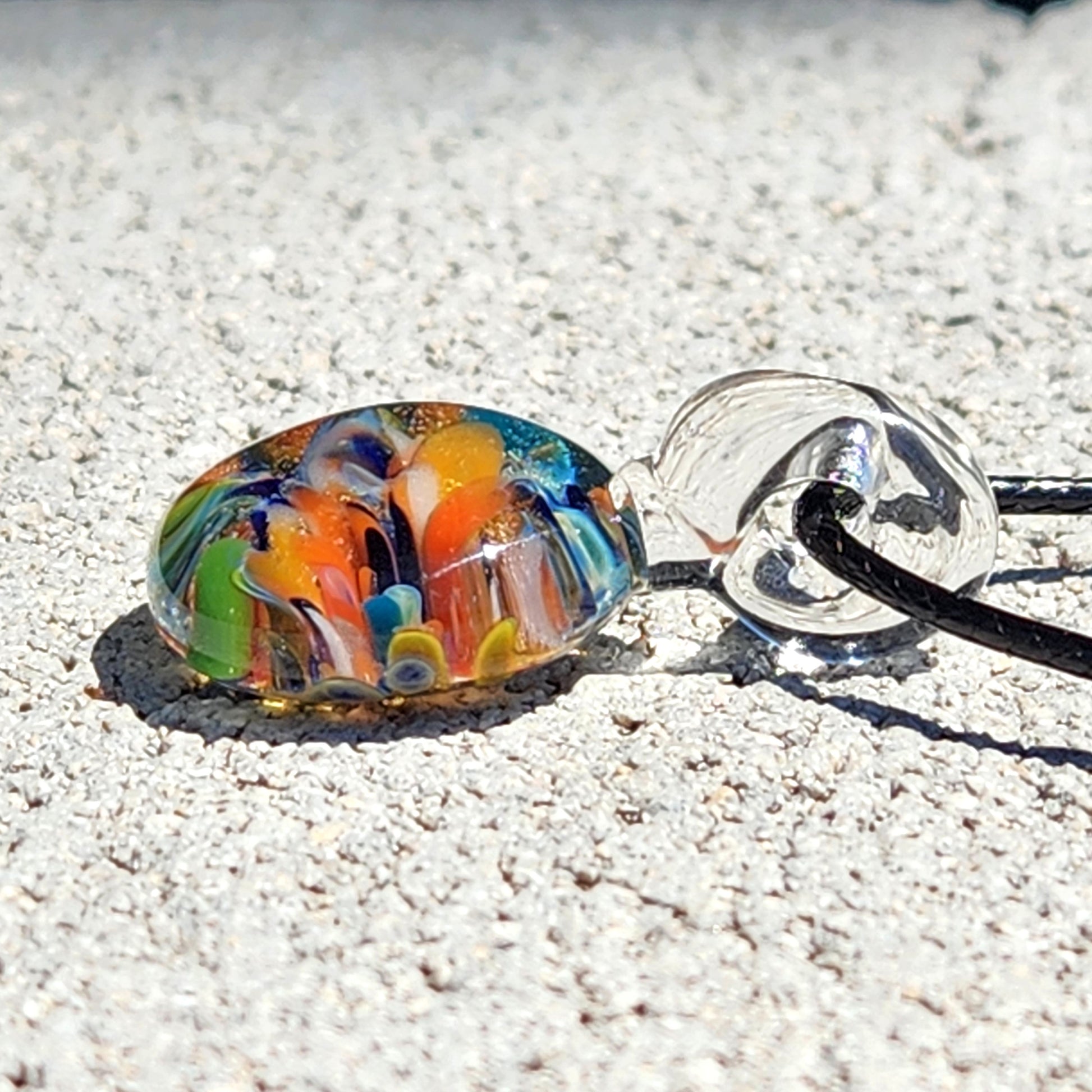 Colorful glass bead on a string against a sandy background