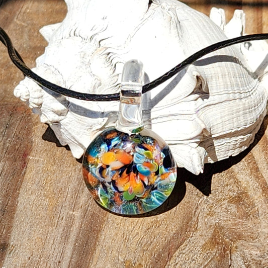 Colorful glass pendant on a black cord with a seashell in the background