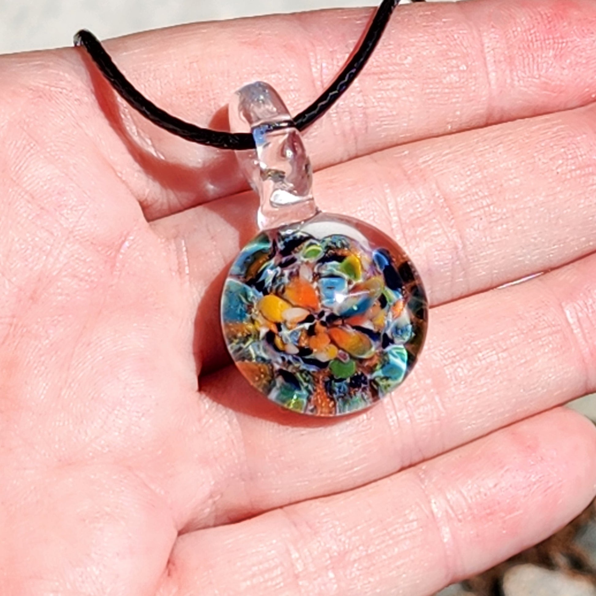 Colorful glass pendant on a hand