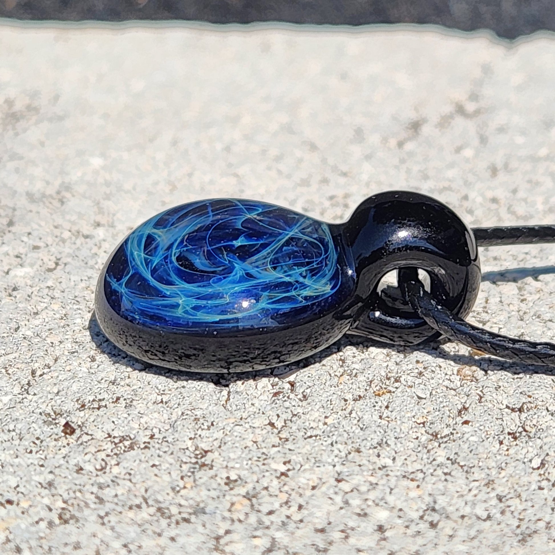 Black glass pendant with blue electric swirl pattern, artisan handmade jewelry on adjustable cord, gift boxed