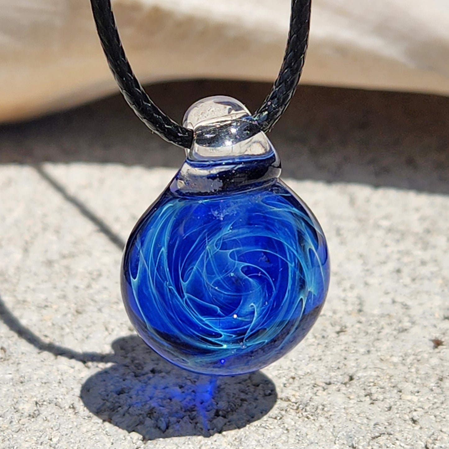 Handmade blue glass pendant necklace with swirling galaxy pattern, silver fuming accents, on adjustable black cord, gift boxed.