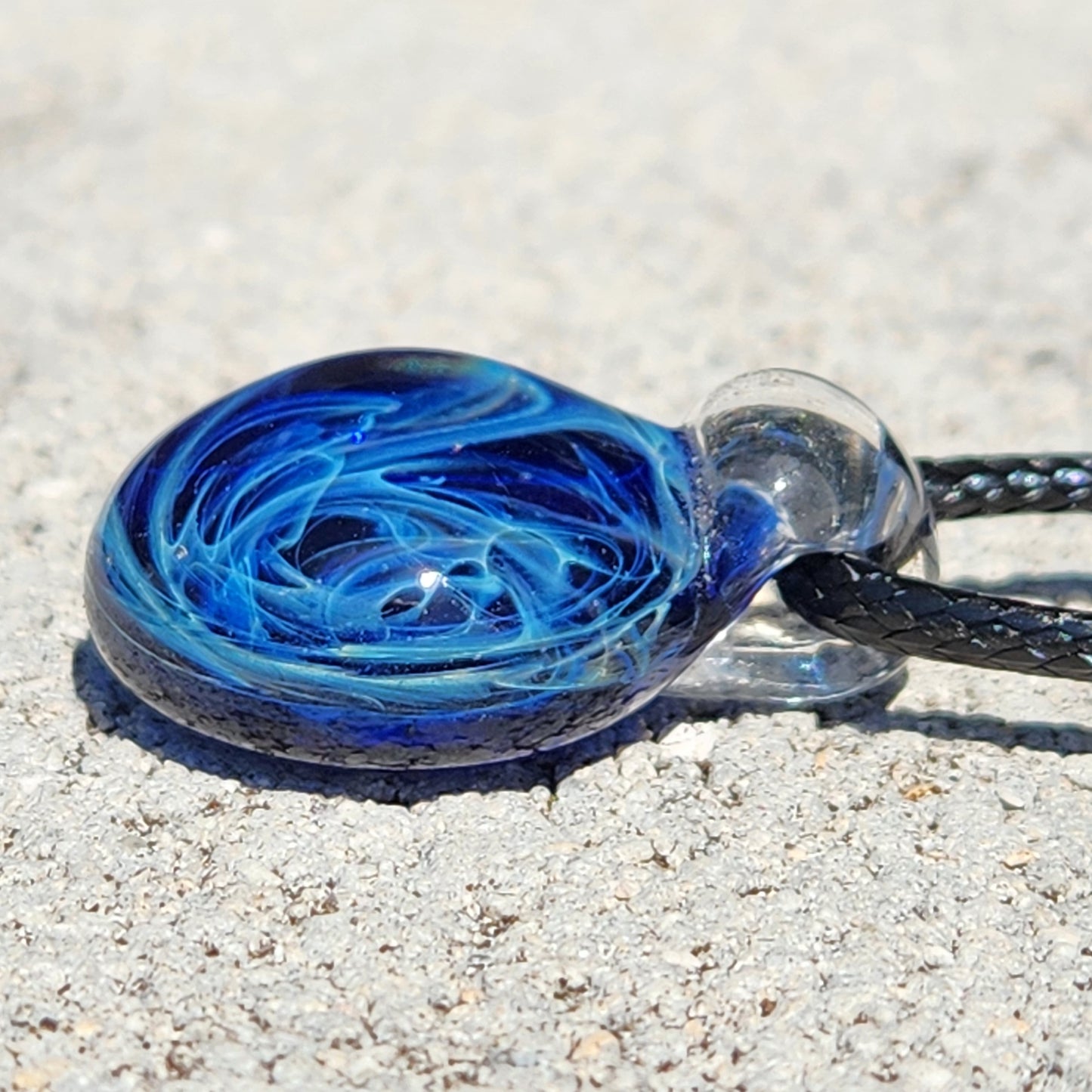 Blue glass galaxy pendant with swirling pattern, handmade silver fumed jewelry, on textured background, gift box included