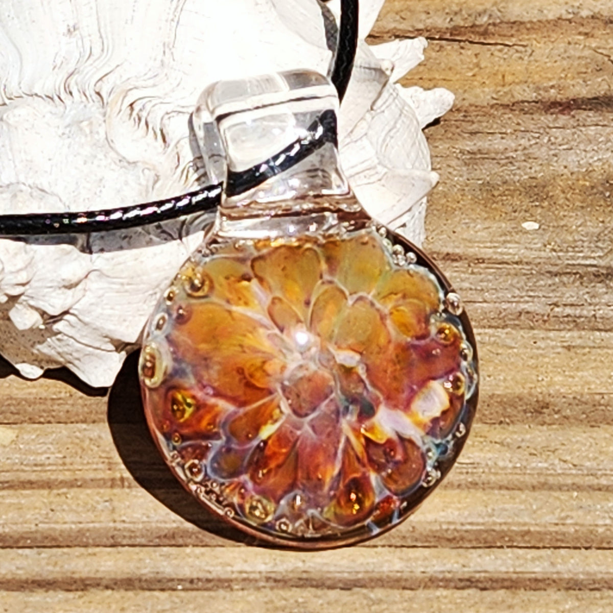 Bottom view of the colorful glass pendant necklace with a black cord, showcasing the intricate sunset design.
