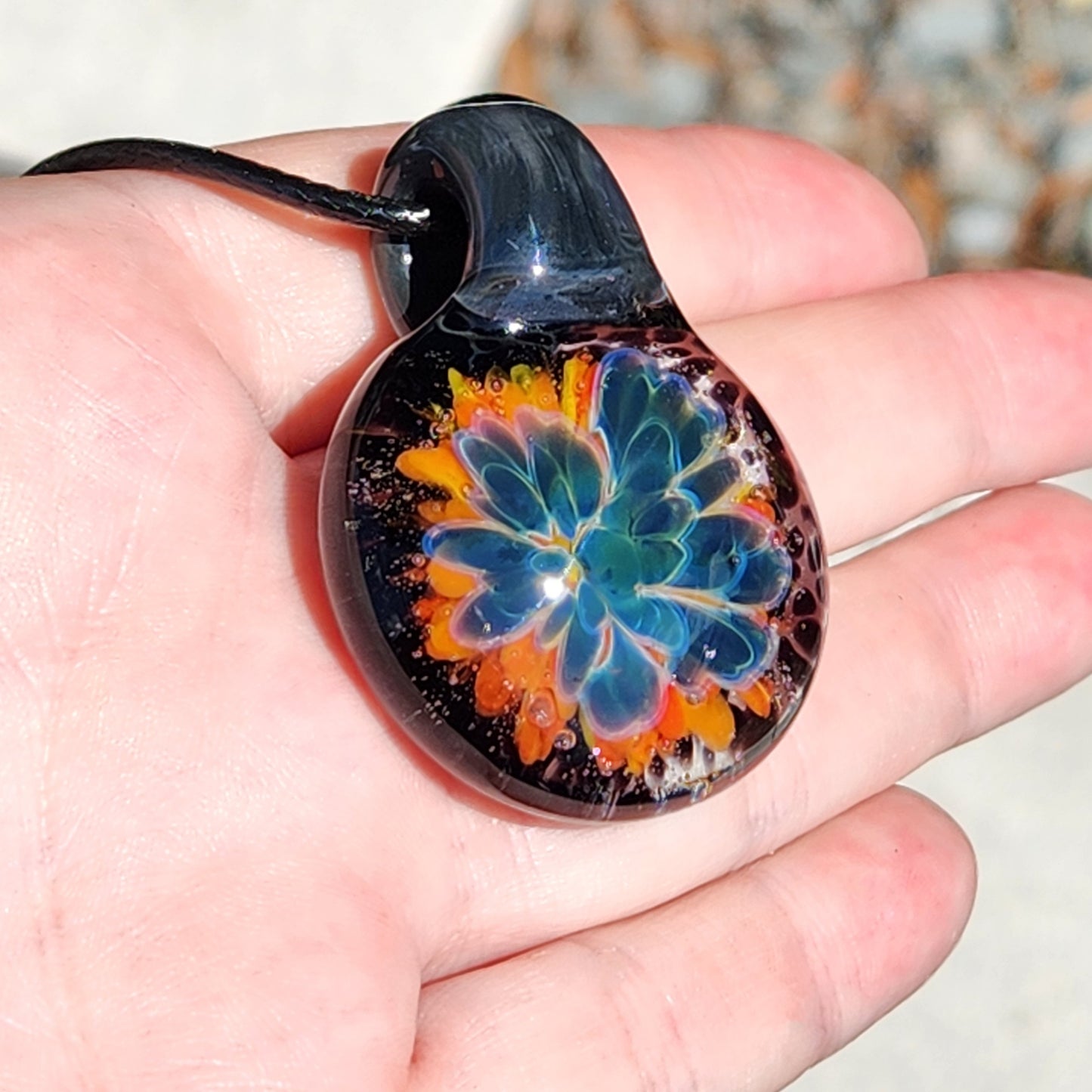 Side angle of the glass pendant necklace, highlighting the detailed flower pattern and glossy finish.