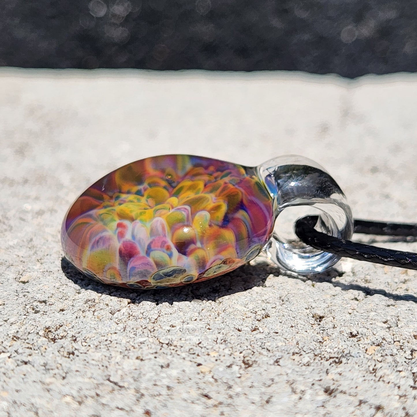 Close-up of the glass pendant with rainbow colors, showing the detailed swirl pattern and glossy finish.