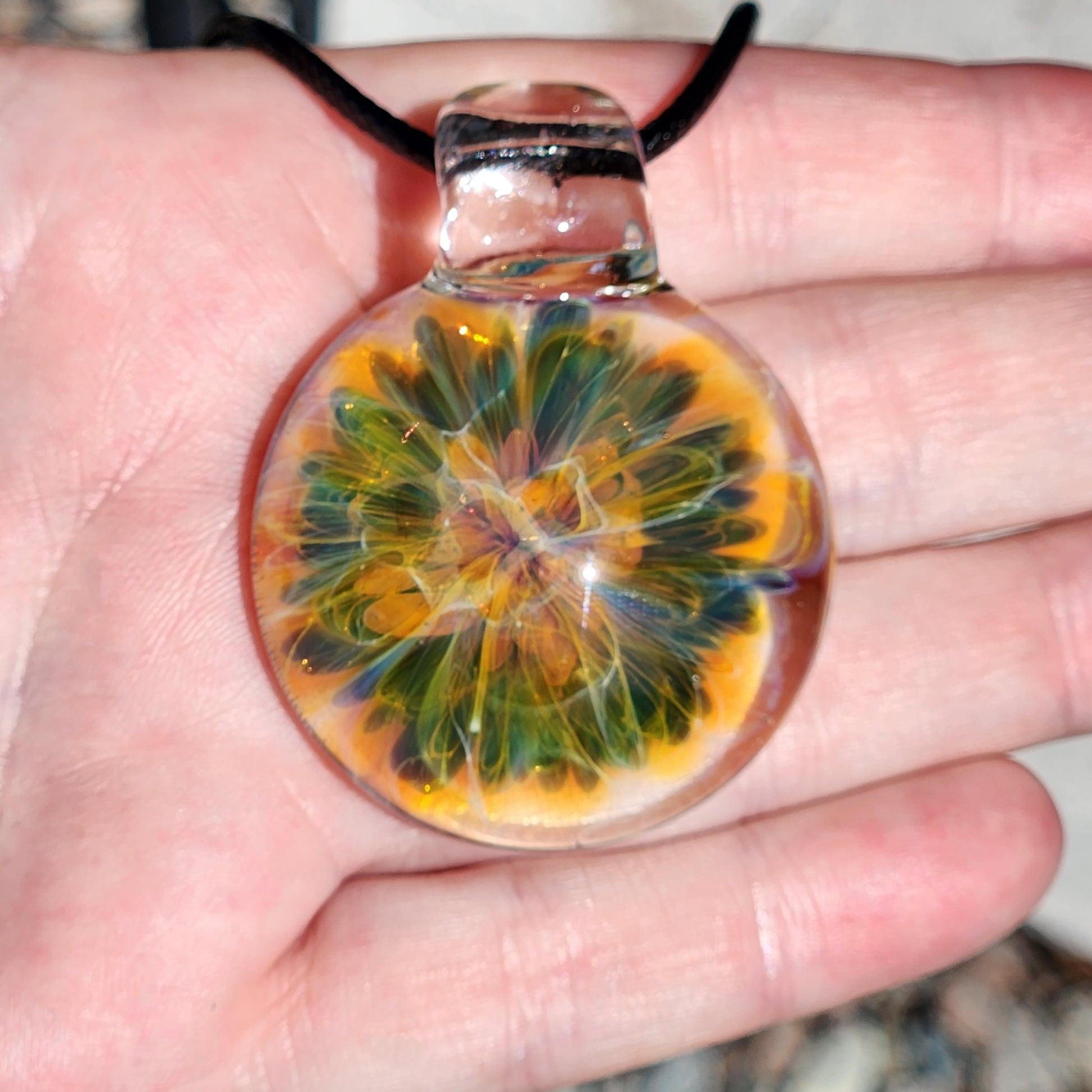 Close-up of the glass pendant showing the detailed swirl pattern and glossy finish, with a black cord and textured background.