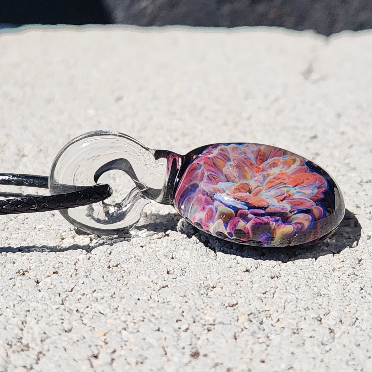Close-up of a handmade glass pendant with multicolor floral design, small lightweight jewelry, ideal for gift-giving