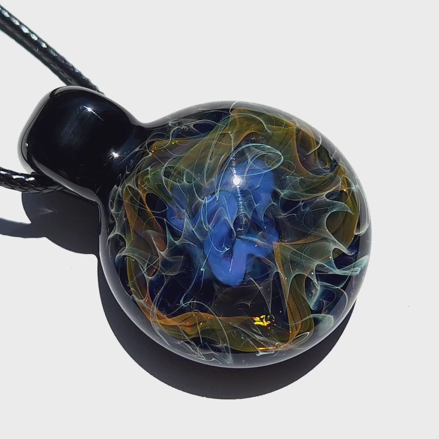 Round handmade glass pendant with vivid blue center and golden swirls, perfect as a unique gift in cosmic jewelry collections.