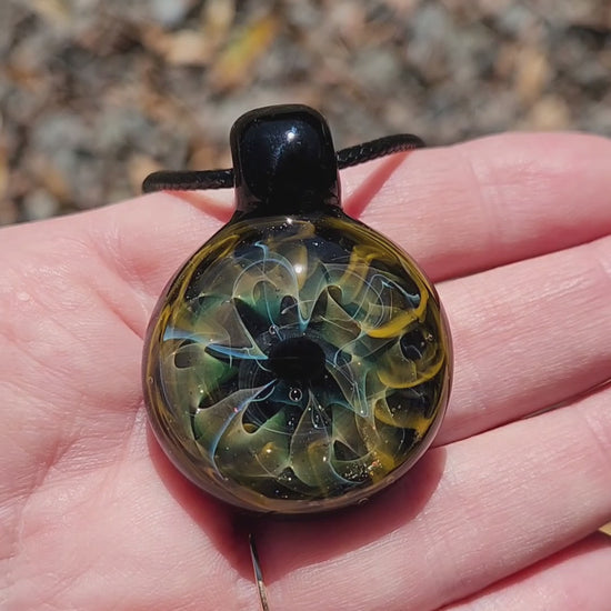Unique handmade blown glass pendant necklace with swirling galaxy design in black, blue, and gold tones. A perfect glass jewelry gift for space lovers.