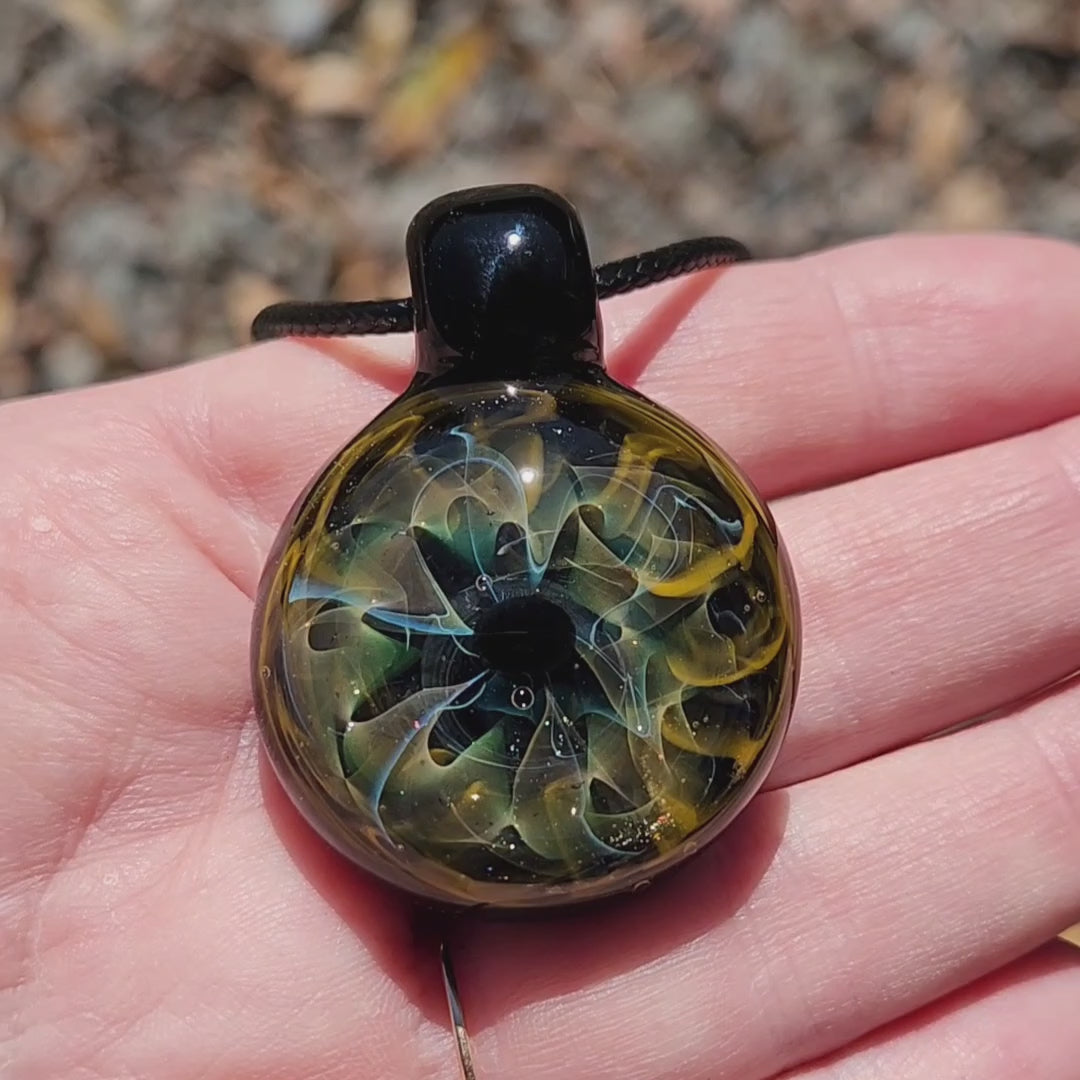 Unique handmade blown glass pendant necklace with swirling galaxy design in black, blue, and gold tones. A perfect glass jewelry gift for space lovers.