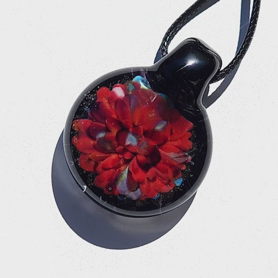 Close-up of radiant red glass pendant necklace with multicolor highlights. Handmade blown glass pendant crafted from strong borosilicate glass.