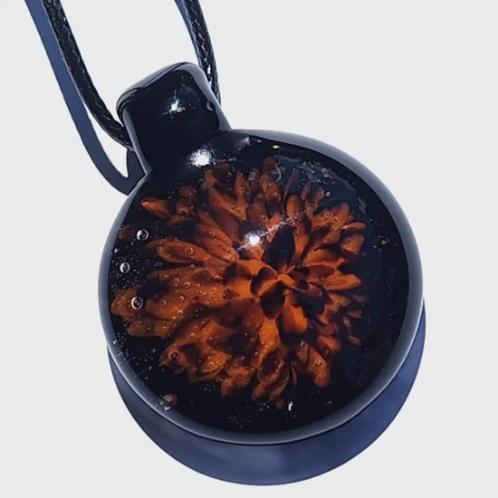 Close-up of the Fiery Glass Pendant Necklace with a glowing orange fire bloom encased in black glass. Handmade Halloween-inspired pendant for fall gifts.