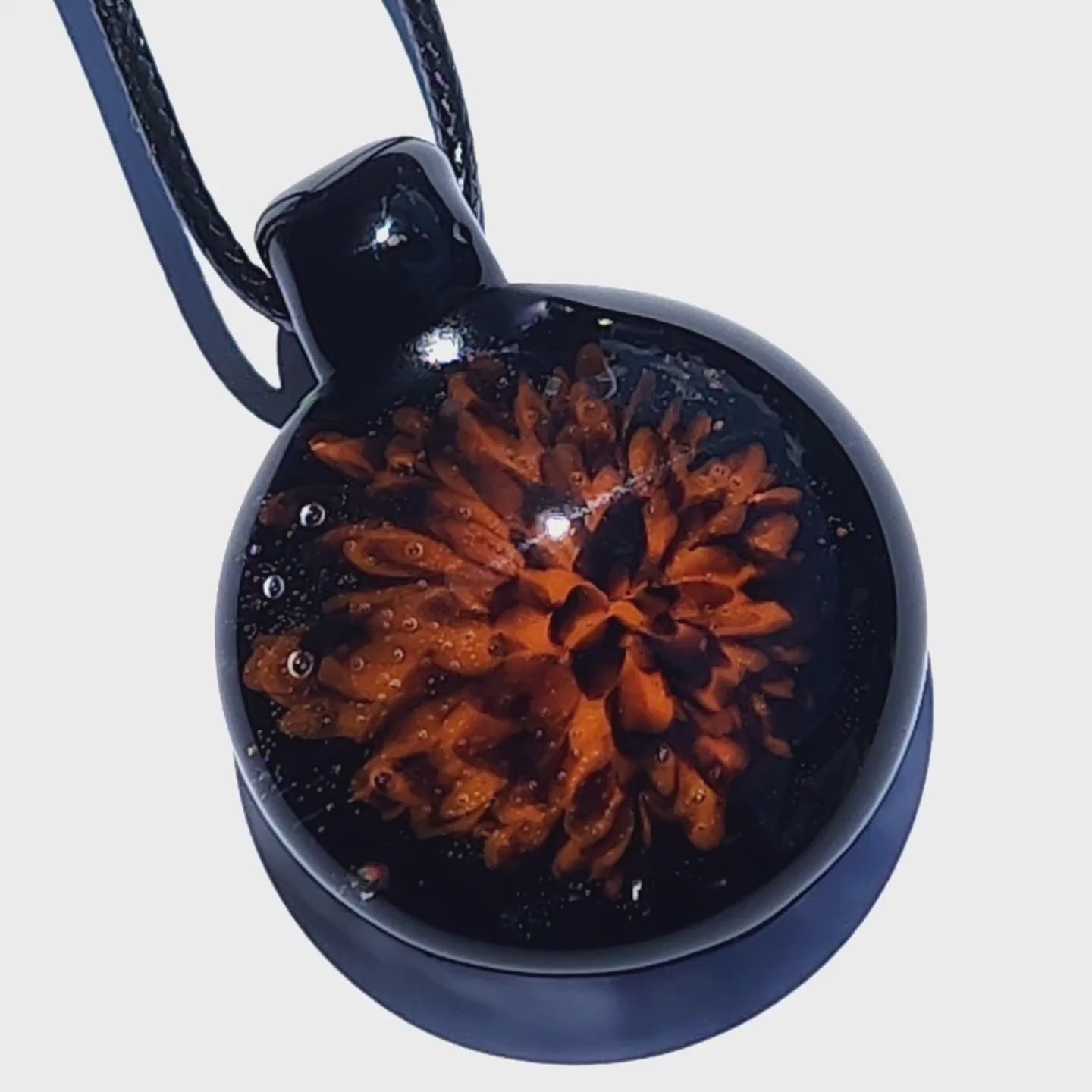 Close-up of the Fiery Glass Pendant Necklace with a glowing orange fire bloom encased in black glass. Handmade Halloween-inspired pendant for fall gifts.