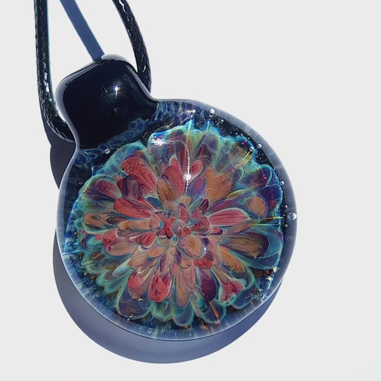Sunlit handmade glass pendant with multicolored flower design. Unique lampworked jewelry gift in deep blue and orange tones.