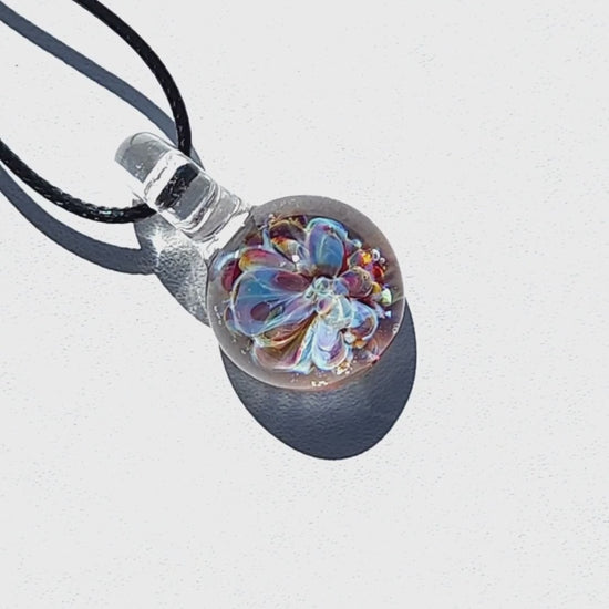 UV Glow Glass Pendant casting a shadow on white background, highlighting the intricate flower design. Handmade blown glass necklace for accessories.