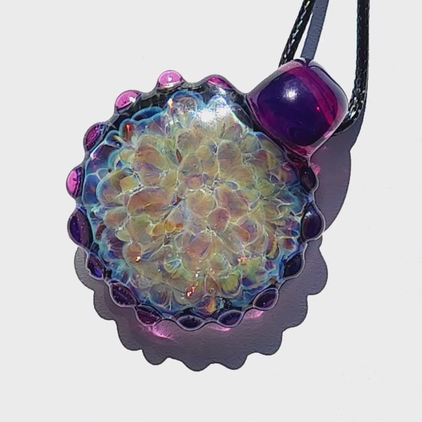 Front view of handmade glass jewelry pendant with metallic rainbow shimmer and scalloped purple edge. One-of-a-kind borosilicate necklace.