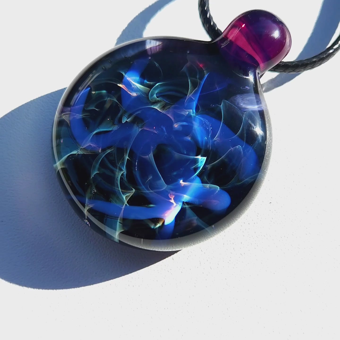 Close-up of Handmade Blue Swirl Glass Pendant Necklace with luminous blue swirls under direct light, highlighting depth and detail.
