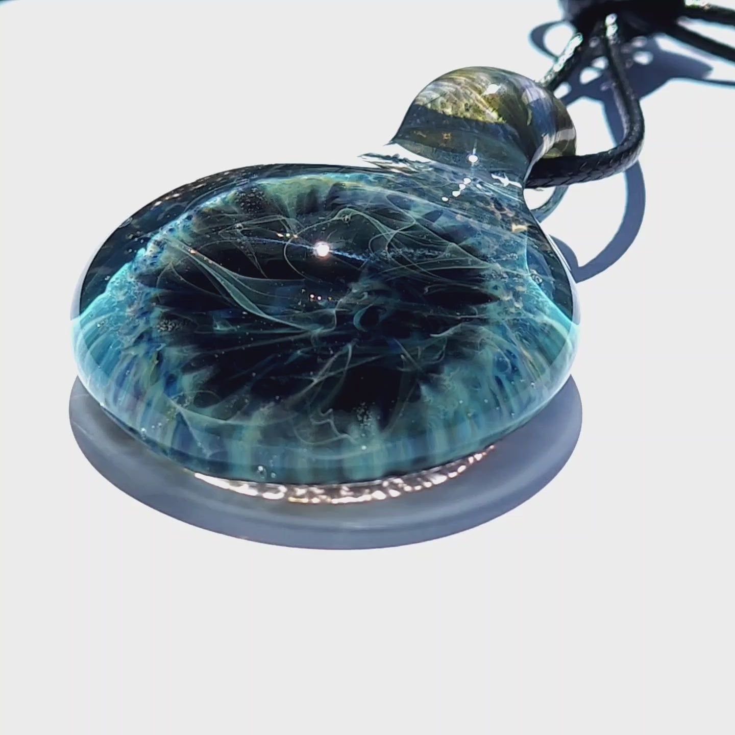 Angled view of Handmade Pendant Necklace – Winter Scene Borosilicate Glass Pendant with glowing blue and black interior swirls.